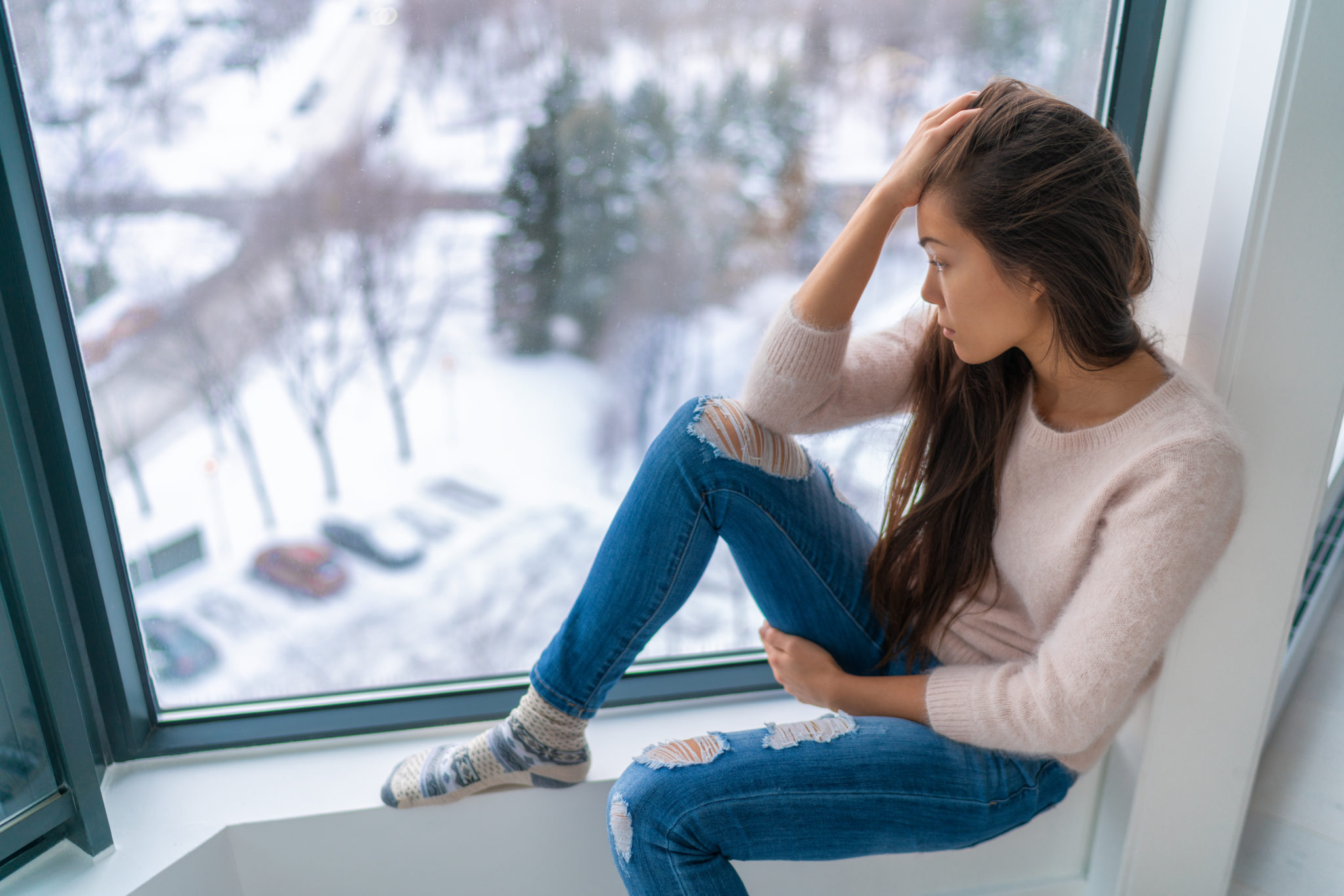 Winter depressed sad girl lonely by home window looking at cold weather ...